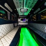 Luxury limousine interior with quilted leather seats and vibrant green neon floor lighting.