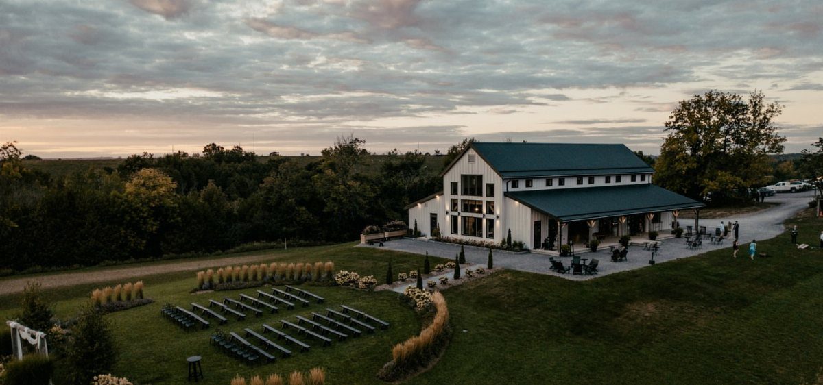 White barn wedding venue with outdoor seating and a patio at sunset.