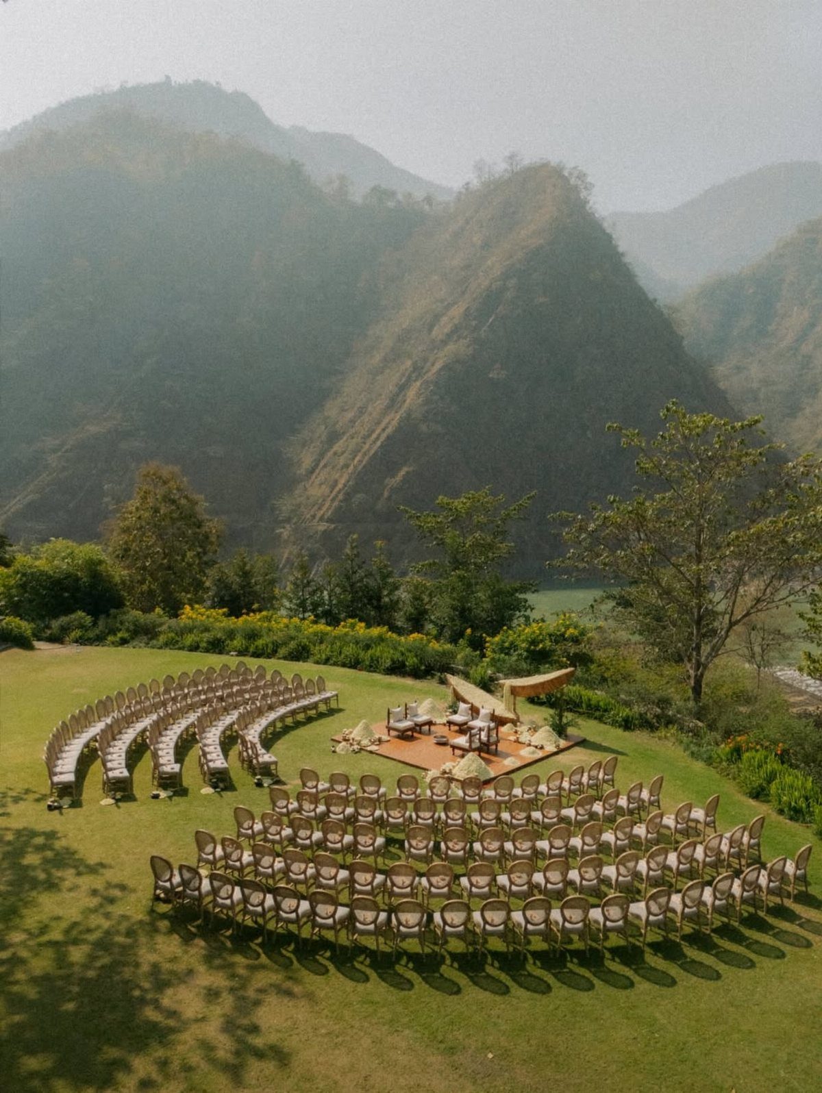 Outdoor wedding ceremony setup with curved seating overlooking a scenic mountain landscape.