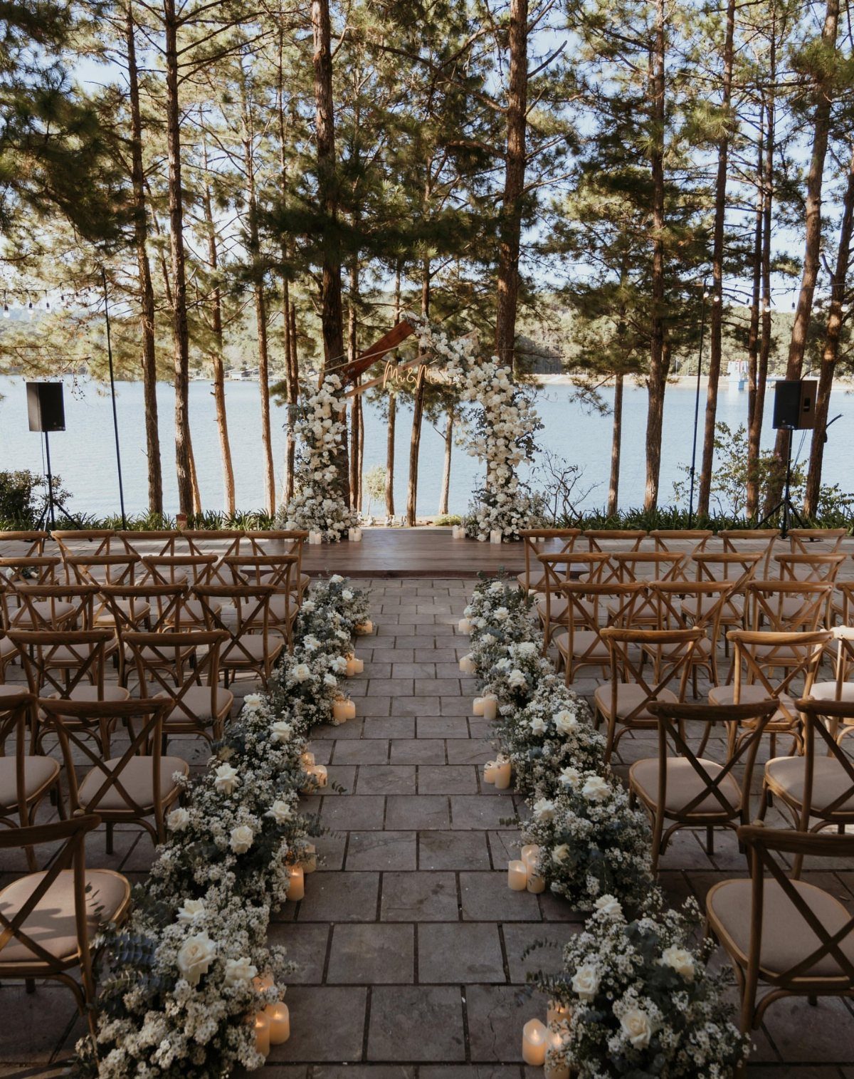 Outdoor wedding ceremony setup with floral aisle and arch overlooking a calm lake