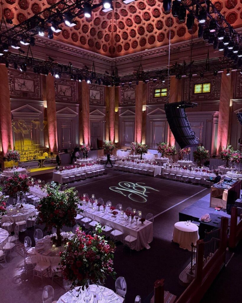 Grand ballroom wedding venue with ornate ceilings, floral centerpieces, and a monogrammed dance floor.