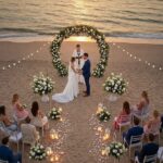 Wedding ceremony on a beach with a circular floral arch at sunset