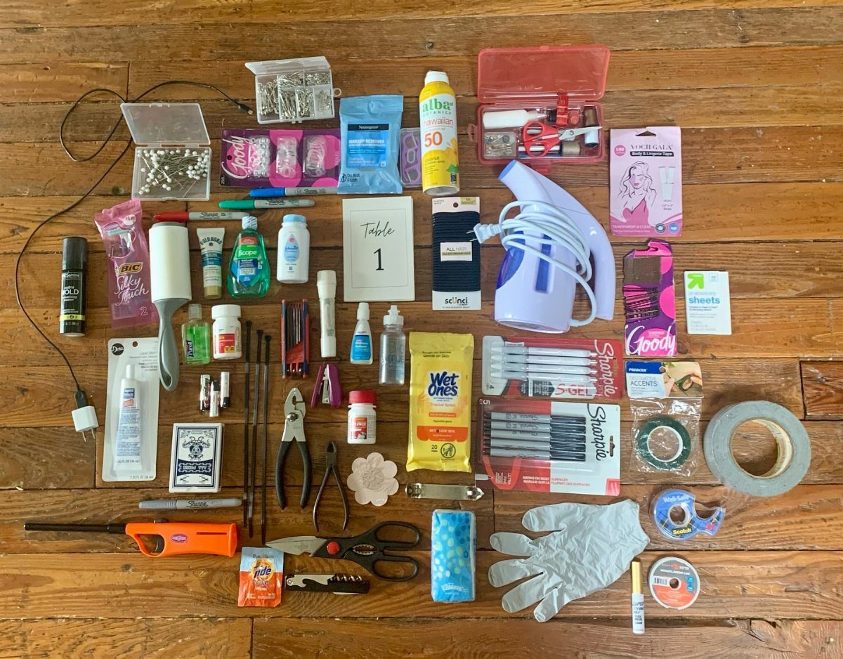 Assorted emergency kit supplies and tools arranged on a rustic wooden floor.