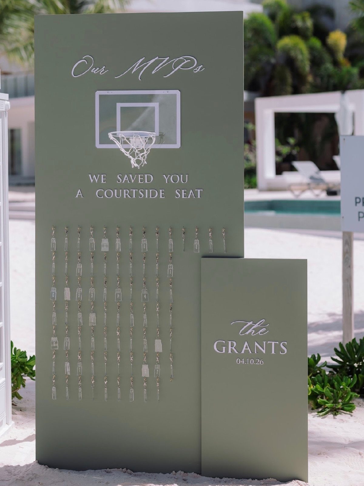 Sage green wedding seating chart with basketball theme and hanging guest name tags.