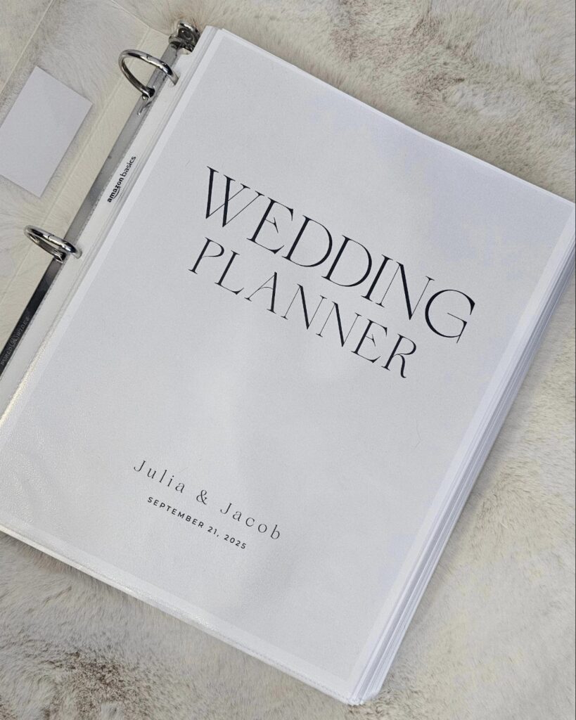 White wedding planner binder with names and date on a furry white background