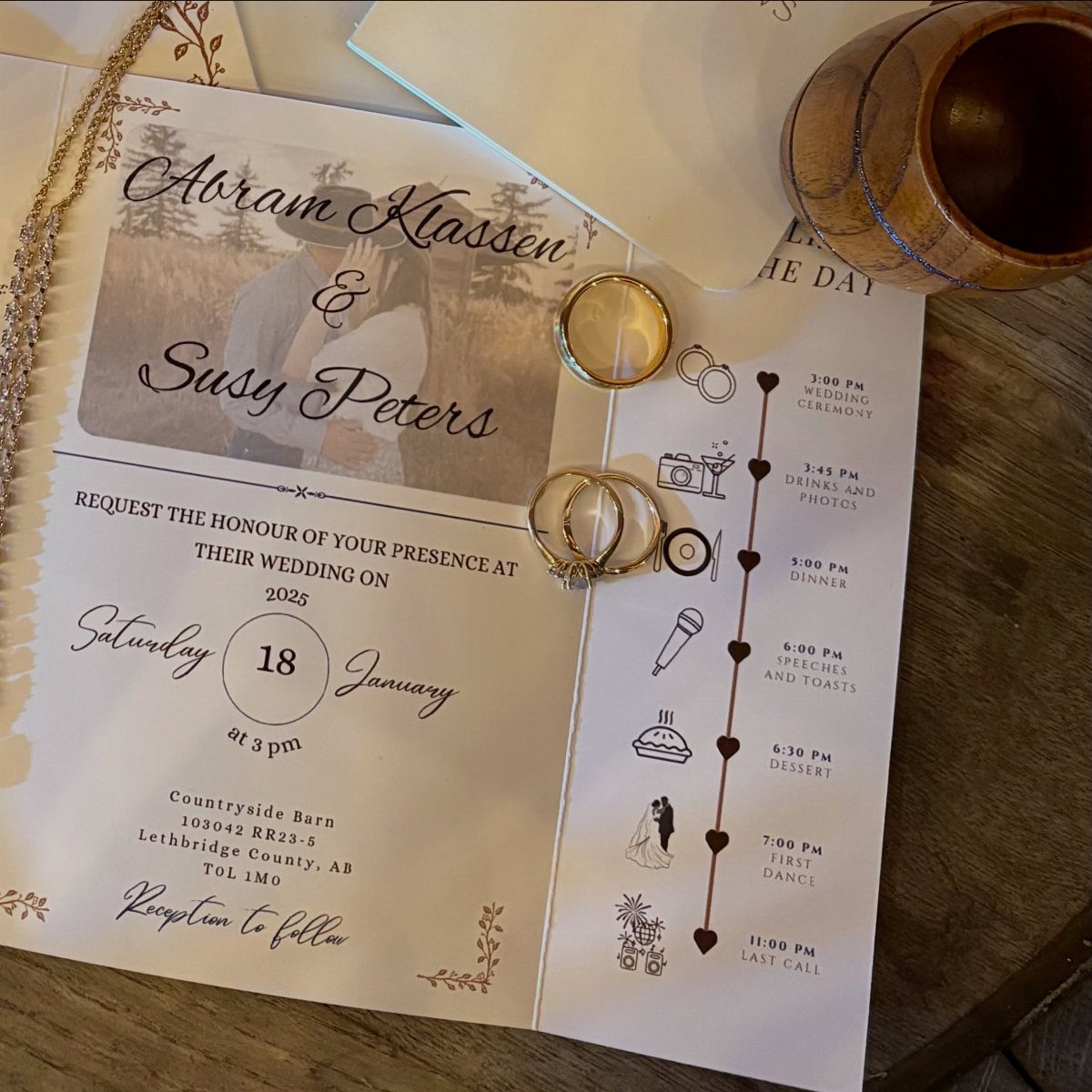 Two gold wedding bands resting on a wedding invitation and event itinerary.