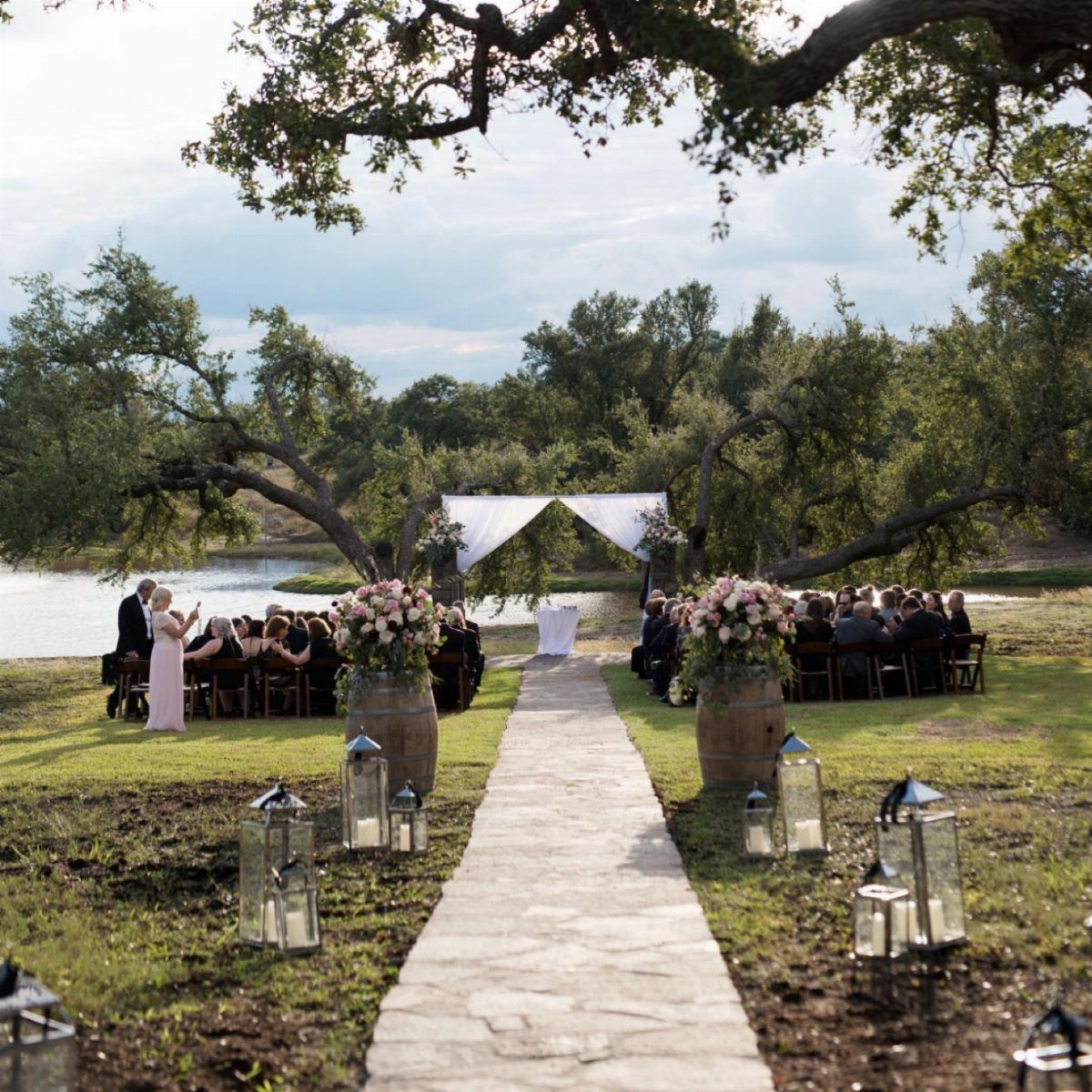 Outdoor wedding ceremony with a stone aisle leading to a lakefront altar.